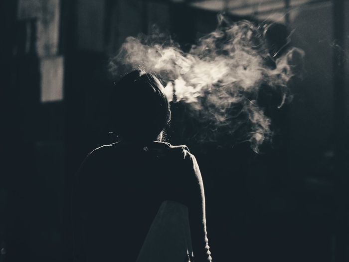 Rear view of person smoking at home