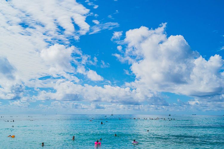 Oahu, hawaii - people in warm waters of waikiki beach against blue sky and clouds
