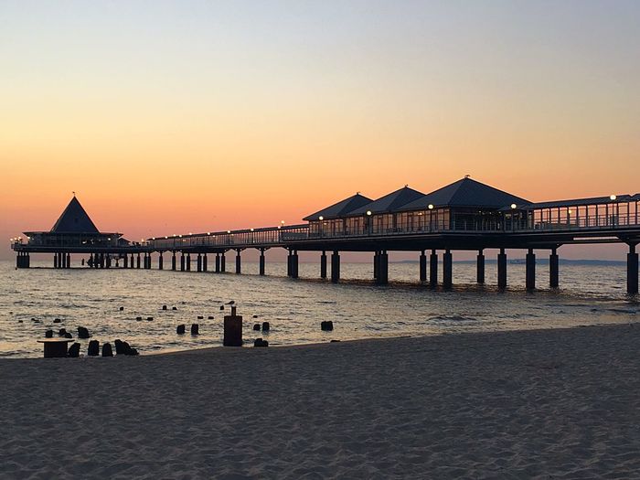 Built structure on beach against clear sky during sunset