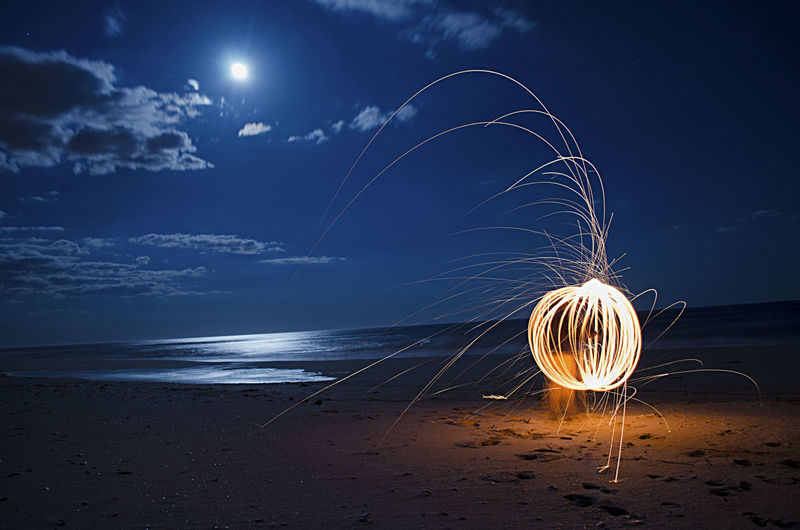 Burning steel wool firework on beach at night