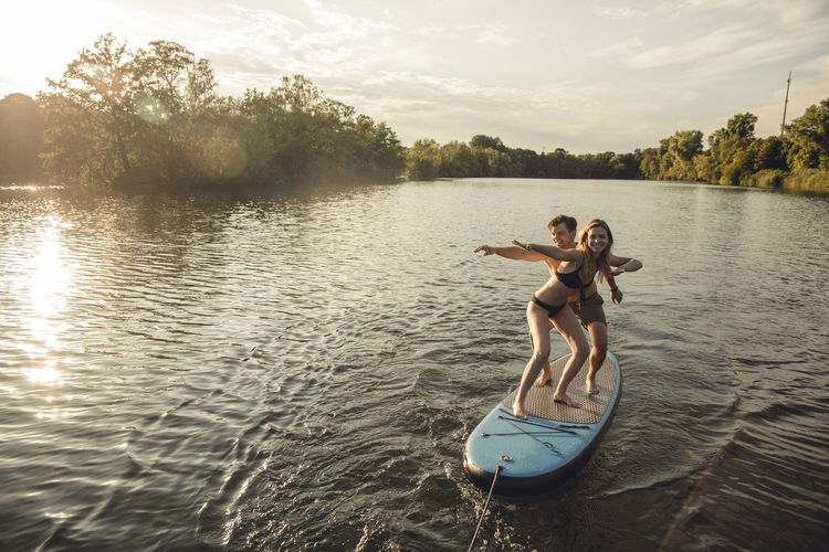 Young couple enjoying summer at the lake, standing on a paddleboard