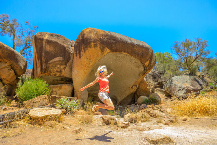 Young woman jumping against rocks