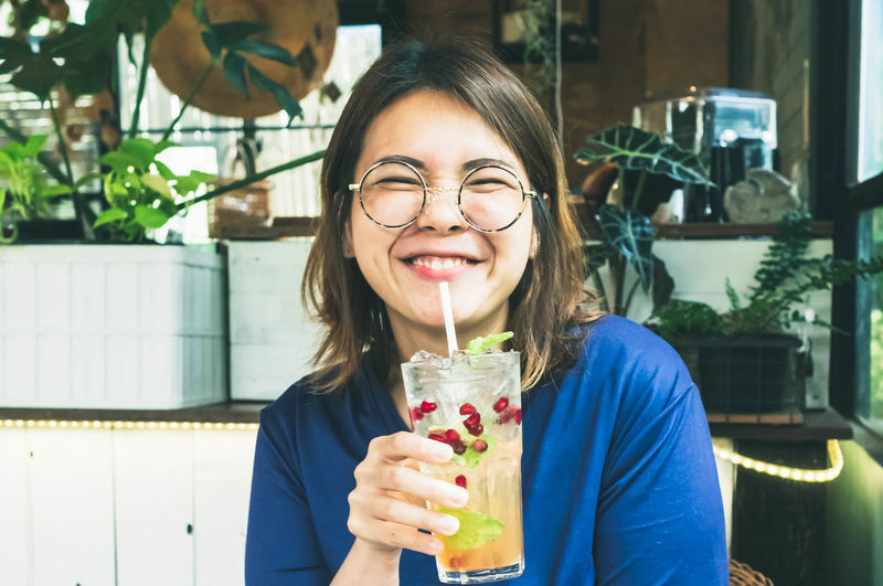 Portrait of smiling woman holding drink in restaurant