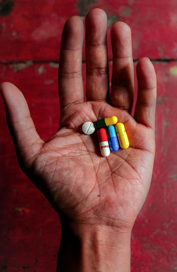 Cropped hand holding multi colored pills