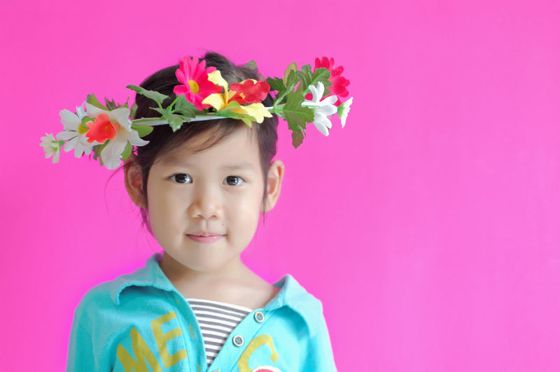 Portrait of girl wearing floral crown against pink background