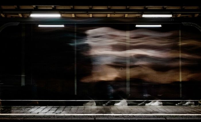 REFLECTION OF WOMAN ON RAILROAD STATION PLATFORM SEEN THROUGH WINDOW