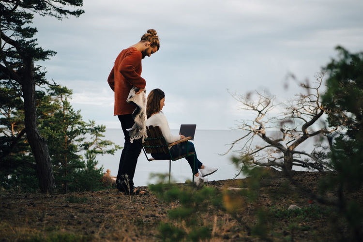 SIDE VIEW OF COUPLE SITTING ON LAND