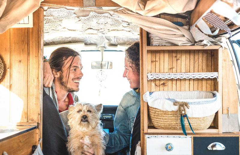 Happy couple with dog sitting in caravan