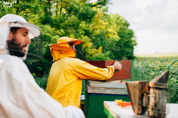 Beekeepers standing by containers on field