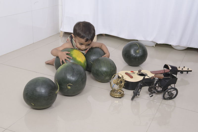 High angle view of boy on floor at home holding watermelon