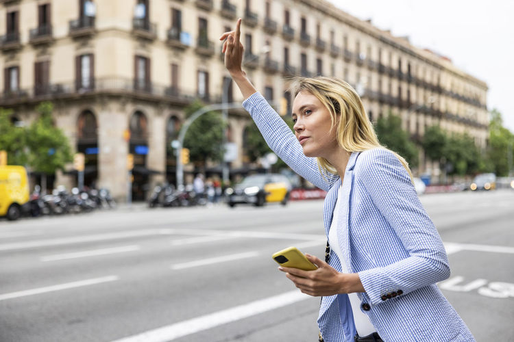 Businesswoman with hand raised hailing ride in city