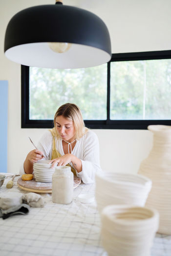 Female pottery artist making a vase in her home studio