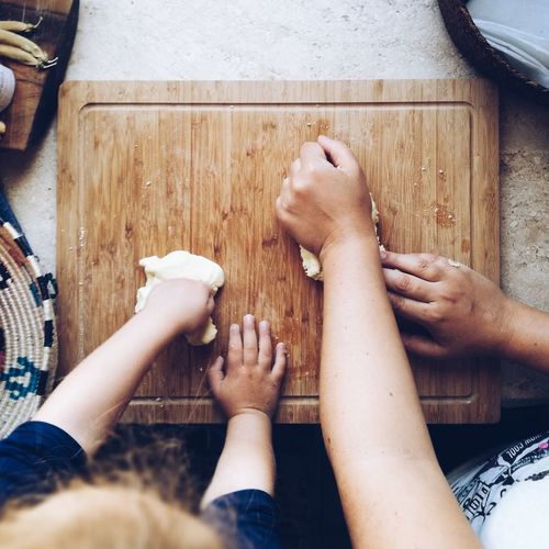 Midsection of mother and daughter kneading dough in kitchen island