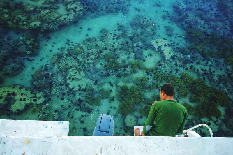 High angle view of man standing by retaining wall over sea