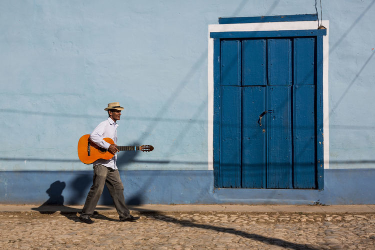 Cuba, man with guitar walking on the street