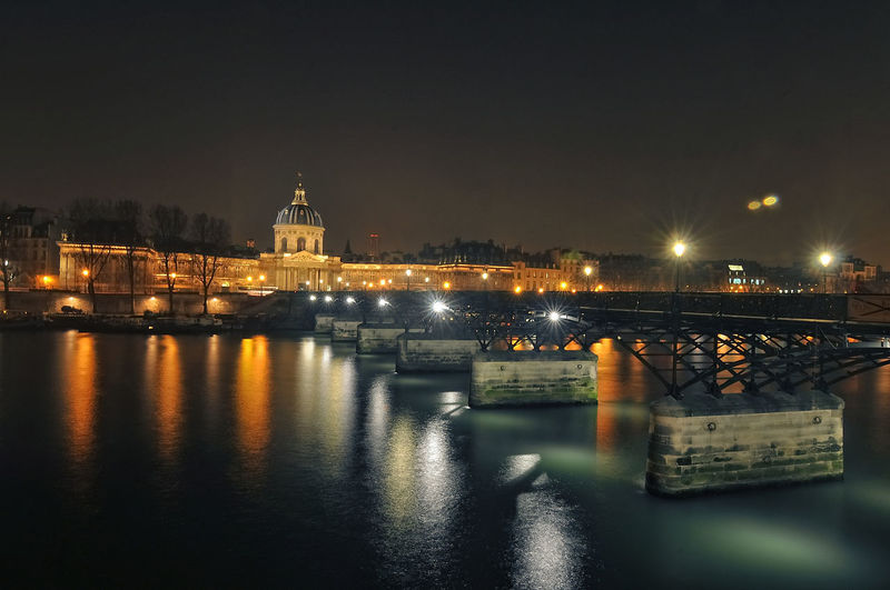 Bridge over seine river against sky in city at night