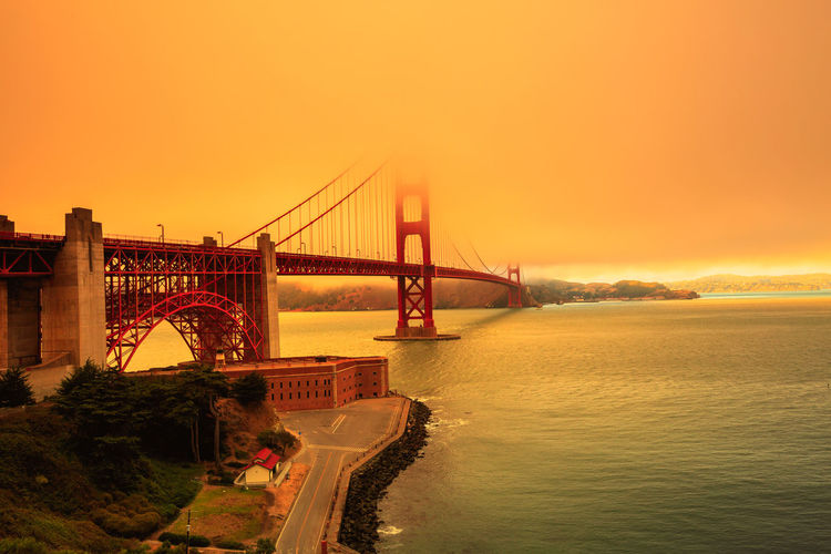 Golden gate bridge over sea against sky during sunset