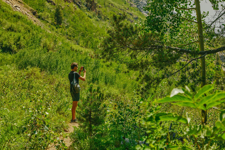 Young man taking a picture on his phone aspen mountain in colorado