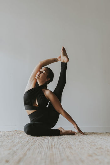 Flexible female yoga instructor with eyes closed exercising at health club