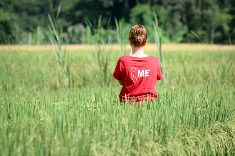 Rear view of woman in t shirt standing amidst plants