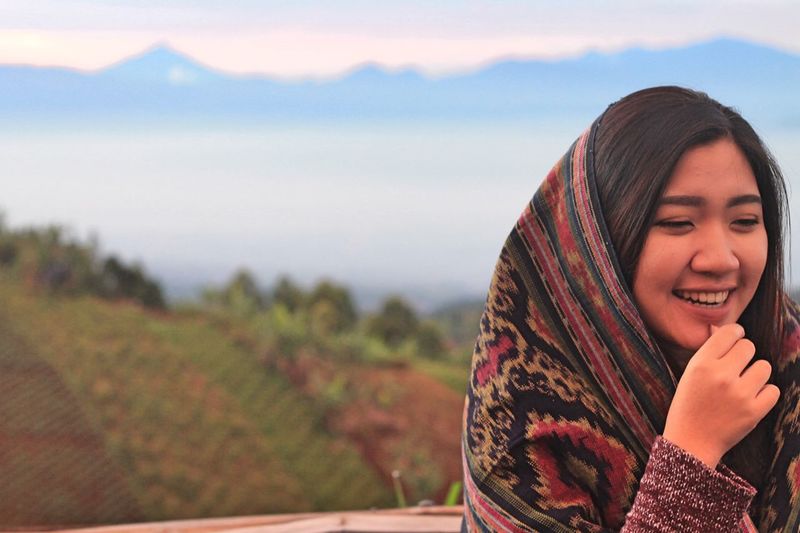 Happy woman with shawl against mountains