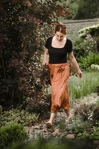 Happy ginger hair woman walking barefoot in the park or garden. freedom and healthy way of life
