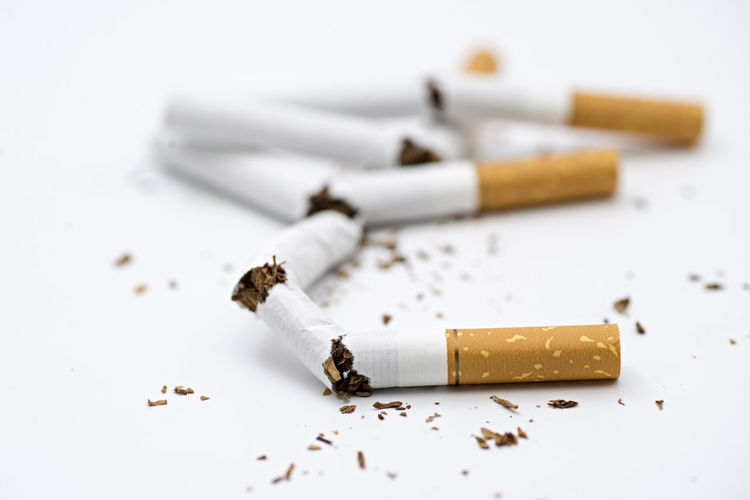 Close-up of crushed cigarettes over white background