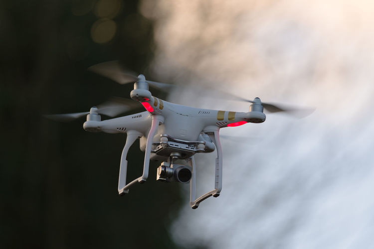 Remote control quadcopter camera drone flying in the evening sky. plain background and motion blur