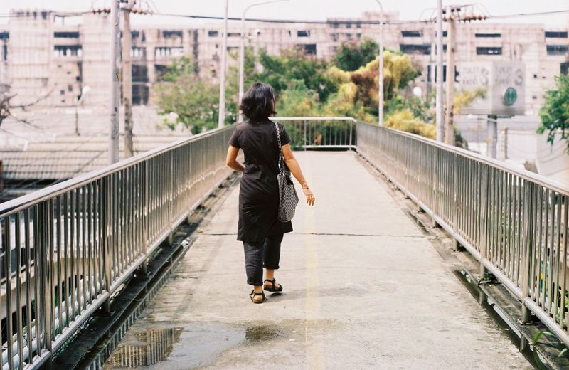 Rear view of a woman walking on footbridge