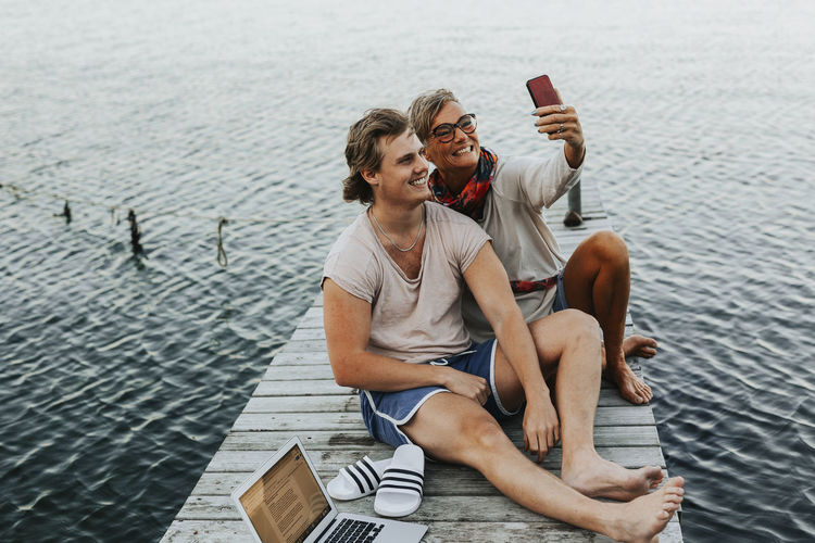 Mother with adult son on jetty taking selfie