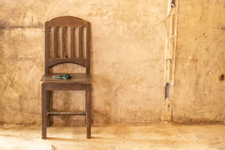 Empty chair and table against wall