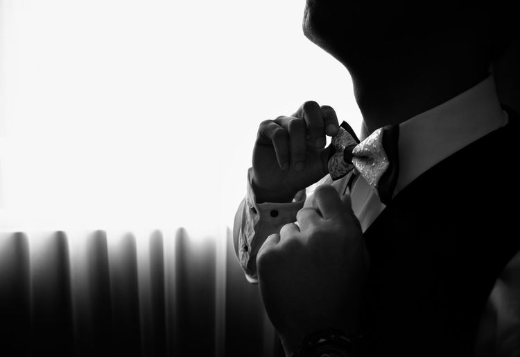 Midsection of man adjusting bow tie