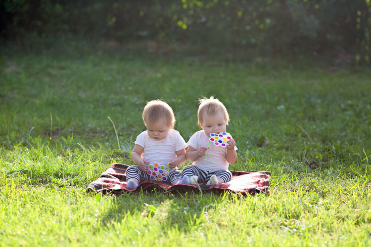 Sisters playing with toys while sitting at lawn