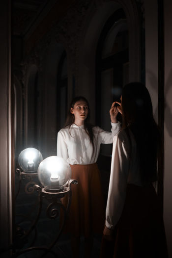 Young woman touching mirror in darkroom
