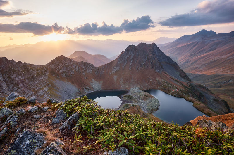 Beautiful mountains at sunset in clouds, gold alpine field, lakes and mountain ranges.