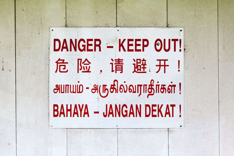 No entry sign saying danger - keep out in 4 languages, english, chinese, tamil and indonesian.