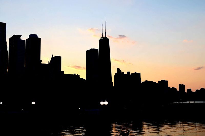 Silhouette of buildings in city at sunset