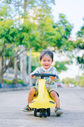 Portrait of cute boy with toy against trees