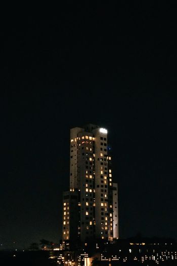 Illuminated buildings against clear sky at night