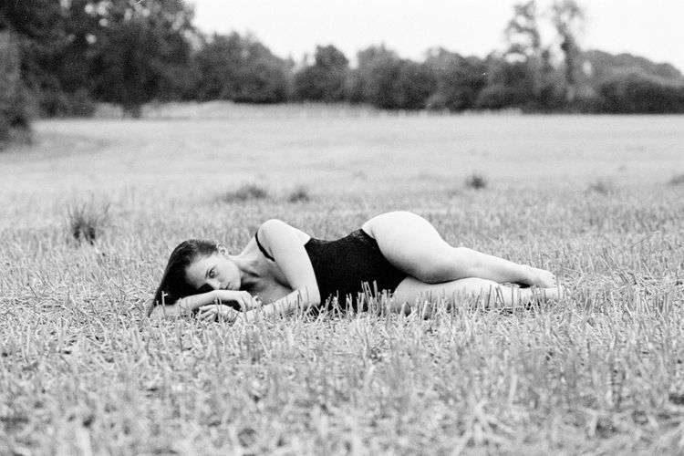 Portrait of woman in swimsuit lying on field