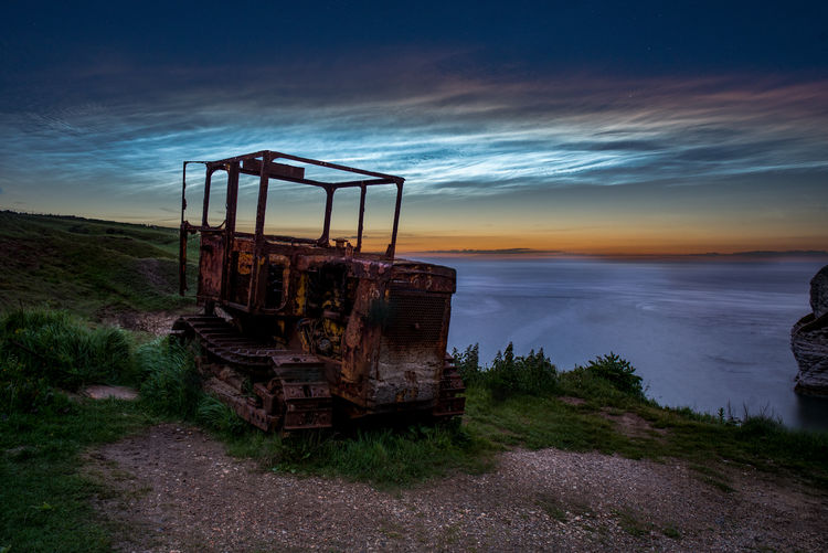 Abandoned ship on beach against sky during sunset