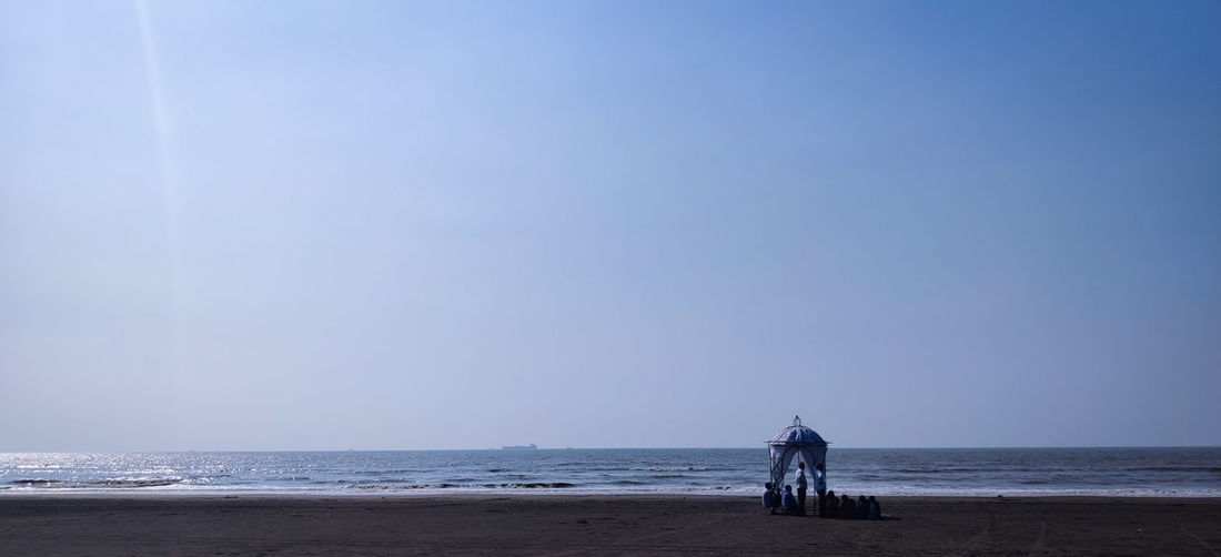 Rear view of men on beach against sky