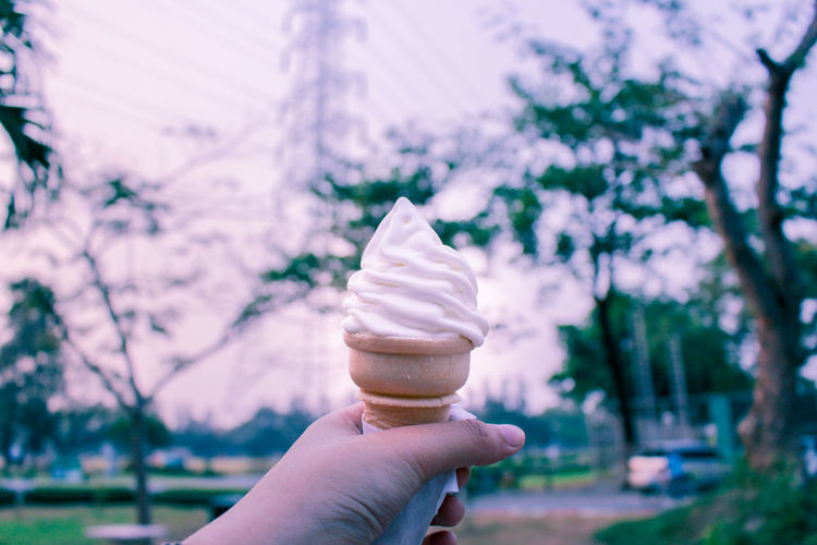 Hand holding ice cream cone outdoors