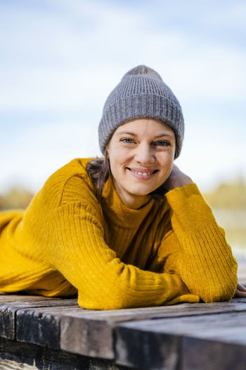 Happy woman wearing knit hat lying on jetty