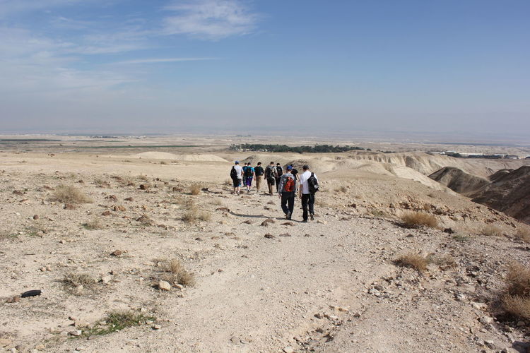 Rear view of people hiking at wadi og against sky