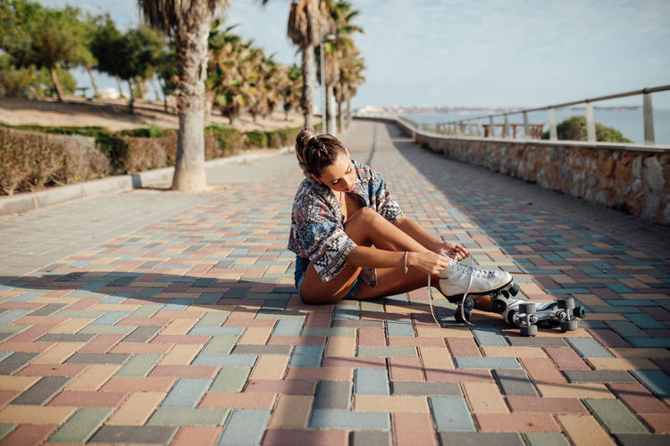 Young woman sitting on footpath