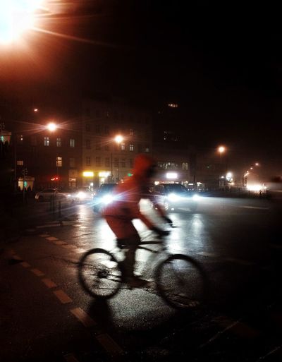 Man riding bicycle on street at night