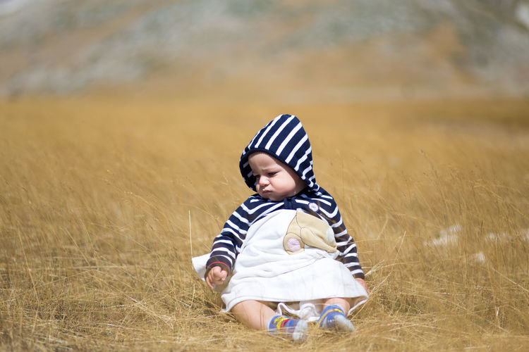 Baby boy sitting on grassy field
