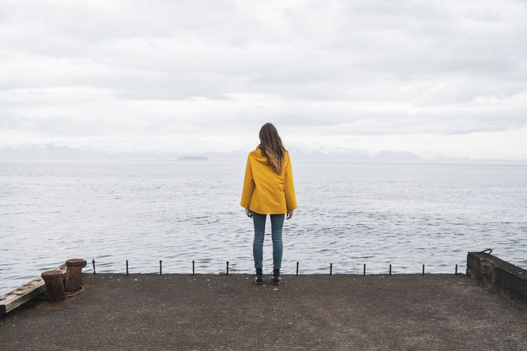 Iceland, woman standing at the sea