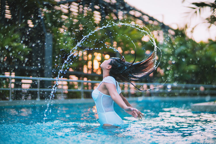 Young woman splashing water in swimming pool